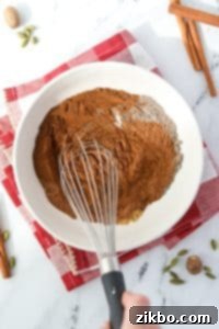 Whisking together various spices to combine into a blend.