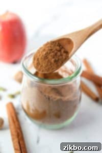 Using a spoon to take apple pie spice from a jar.