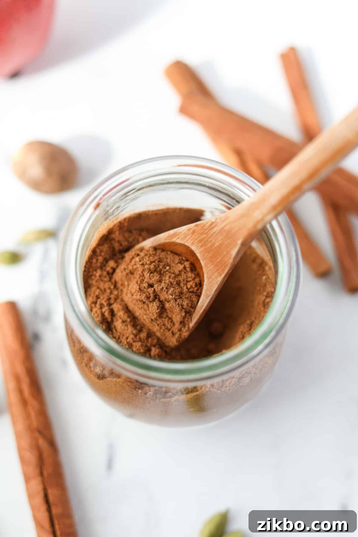 A small spoon taking a portion of apple spice from a jar, showcasing its texture and readiness.