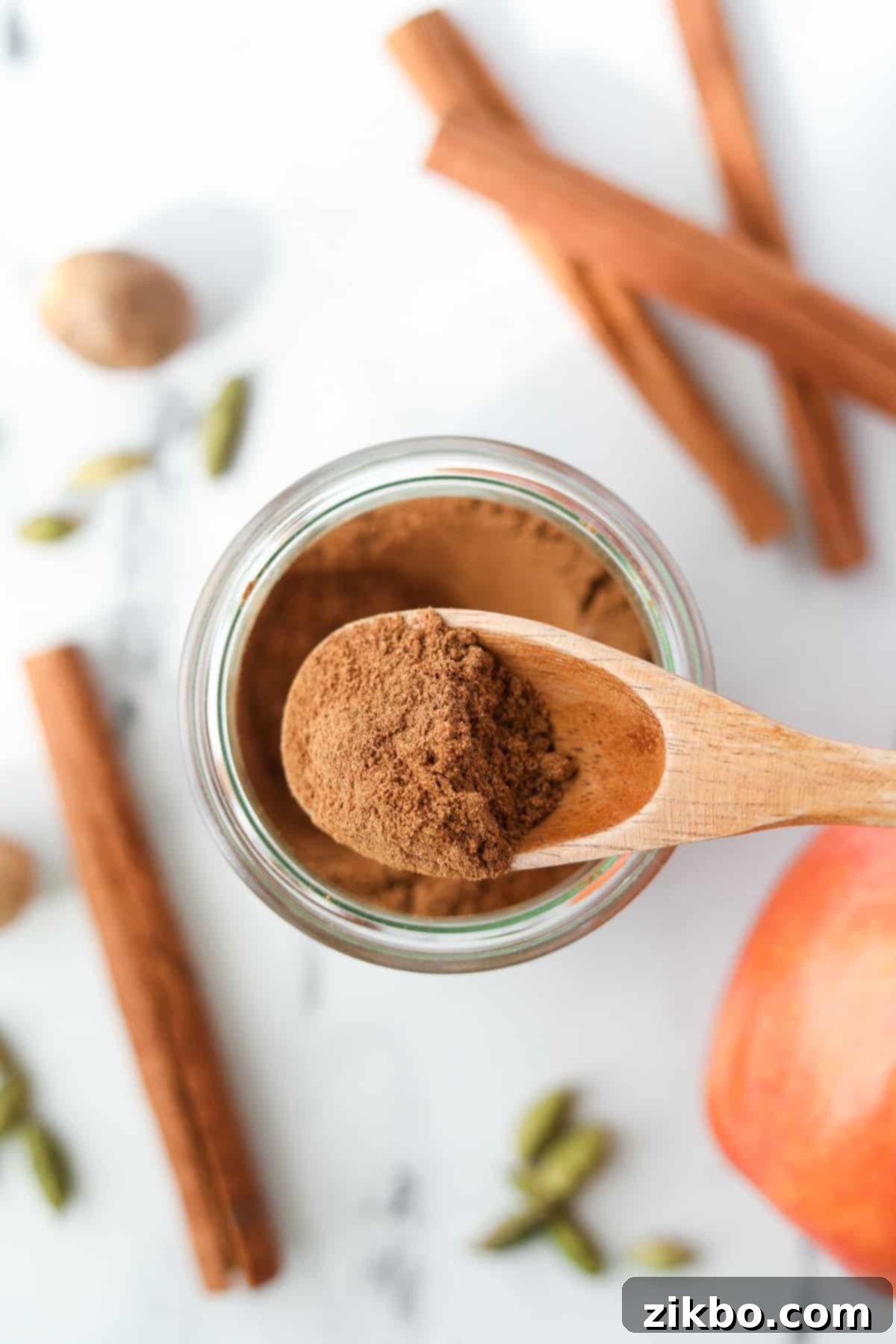 A spoon taking a small amount of homemade spice blend from a jar, ready for baking.