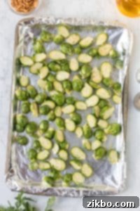 Sliced brussels sprouts laying on a foil-lined tray.