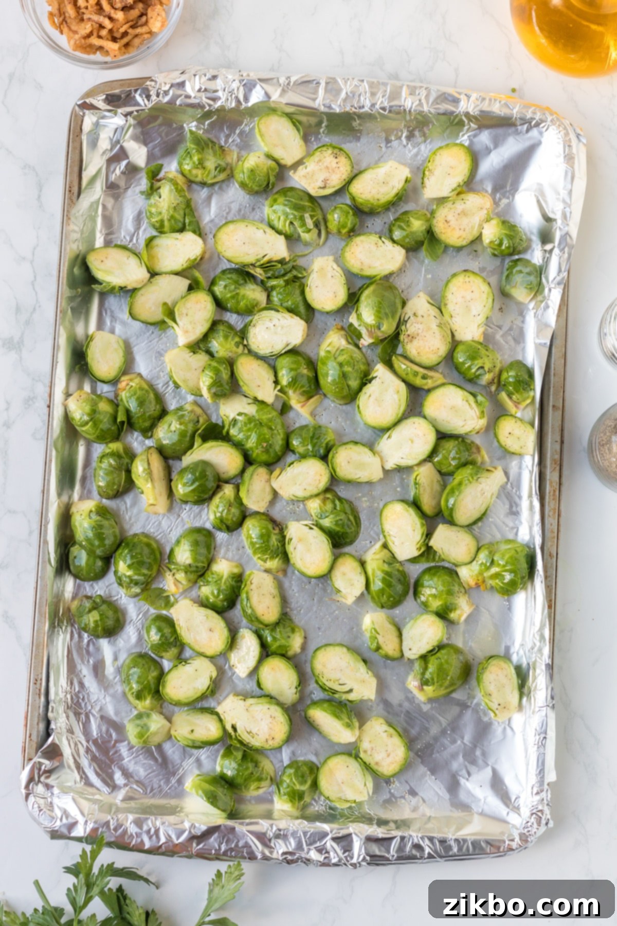 Sliced brussels sprouts laying on a foil-lined tray.
