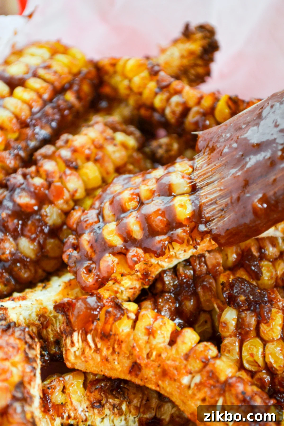 Air fryer corn ribs being brushed with savory barbeque sauce, showing the final luscious glaze.