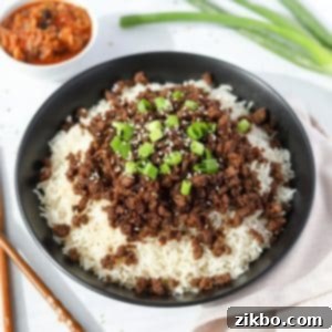 A bowl of rice topped with Korean ground beef, green onions, and sesame seeds.