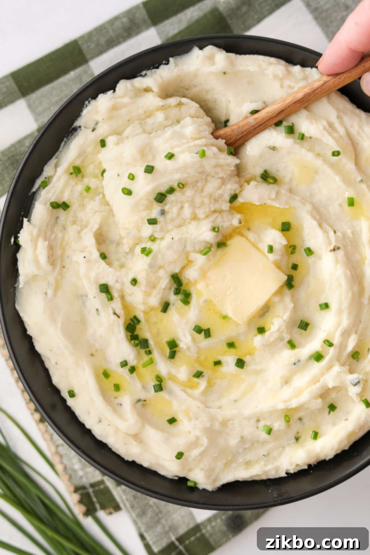 A beautifully presented bowl of creamy Boursin mashed potatoes, elegantly topped with a generous sprinkle of vibrant green chopped chives.