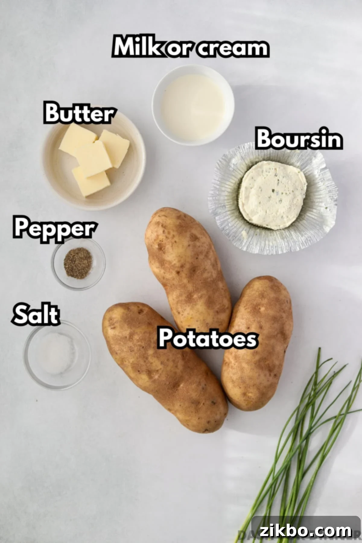 The simple ingredients needed to make creamy Boursin mashed potatoes: russet potatoes, a round of Boursin cheese, heavy cream, butter, ground black pepper, and salt.