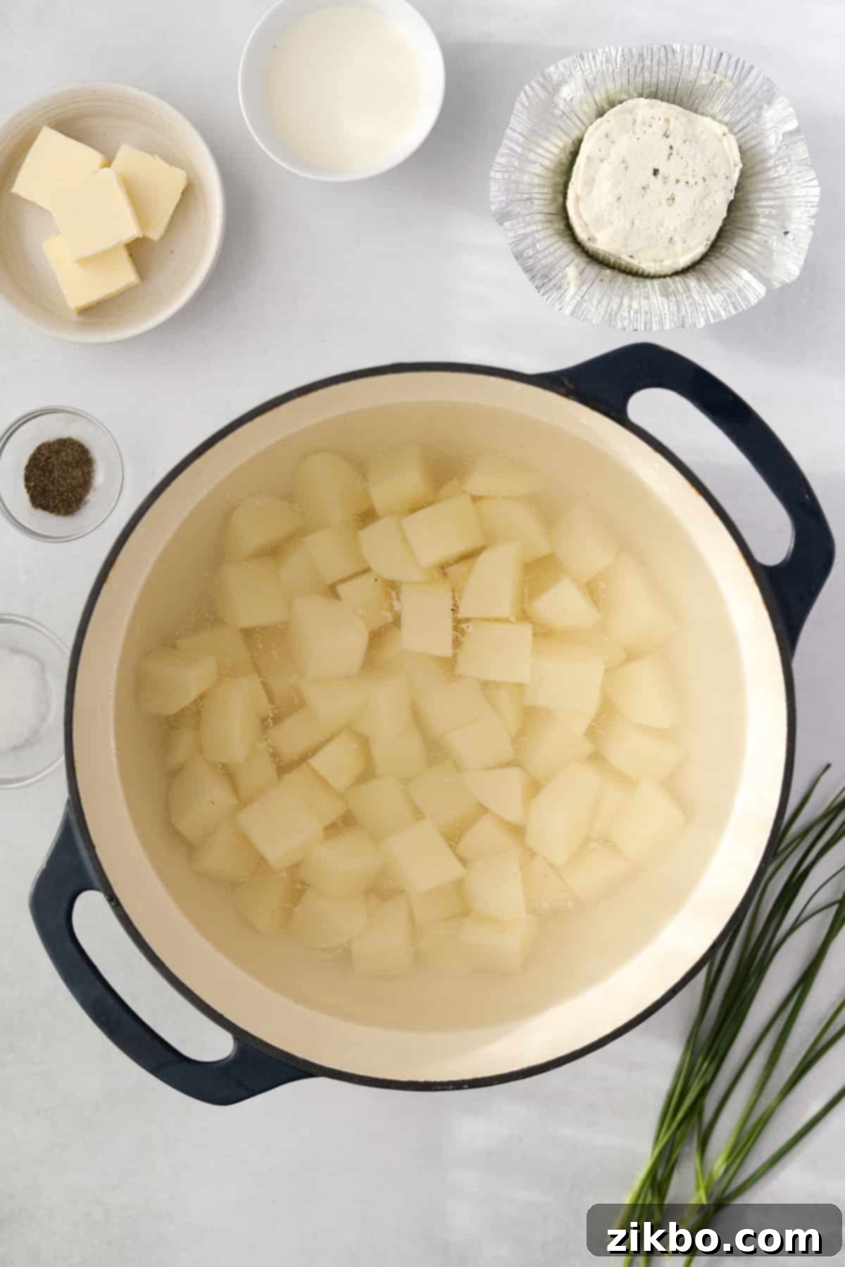 A Dutch oven filled with uniformly cubed raw russet potatoes, ready for boiling.