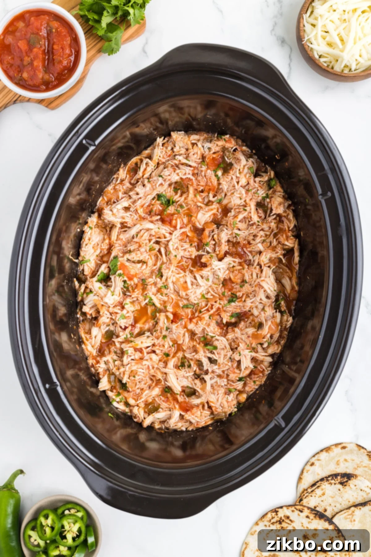 Tender Slow Cooker Salsa Chicken 2 A slow cooker filled with shredded salsa chicken, ready to be served for a quick and easy meal.