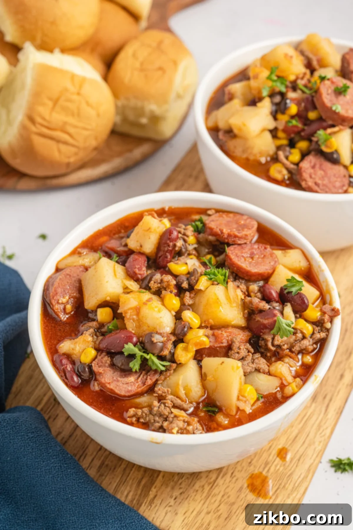 A bowl of hearty ground beef stew made with potatoes, corn, and sausages.