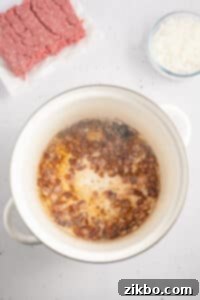 A large pot with onions cooking in bacon fat.