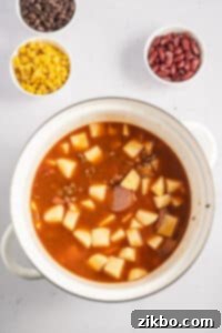 A soup pot filled with a savory broth and cubed potatoes.