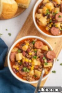 An overhead view of two bowls of hearty soup, containing ground beef, potatoes, and corn.