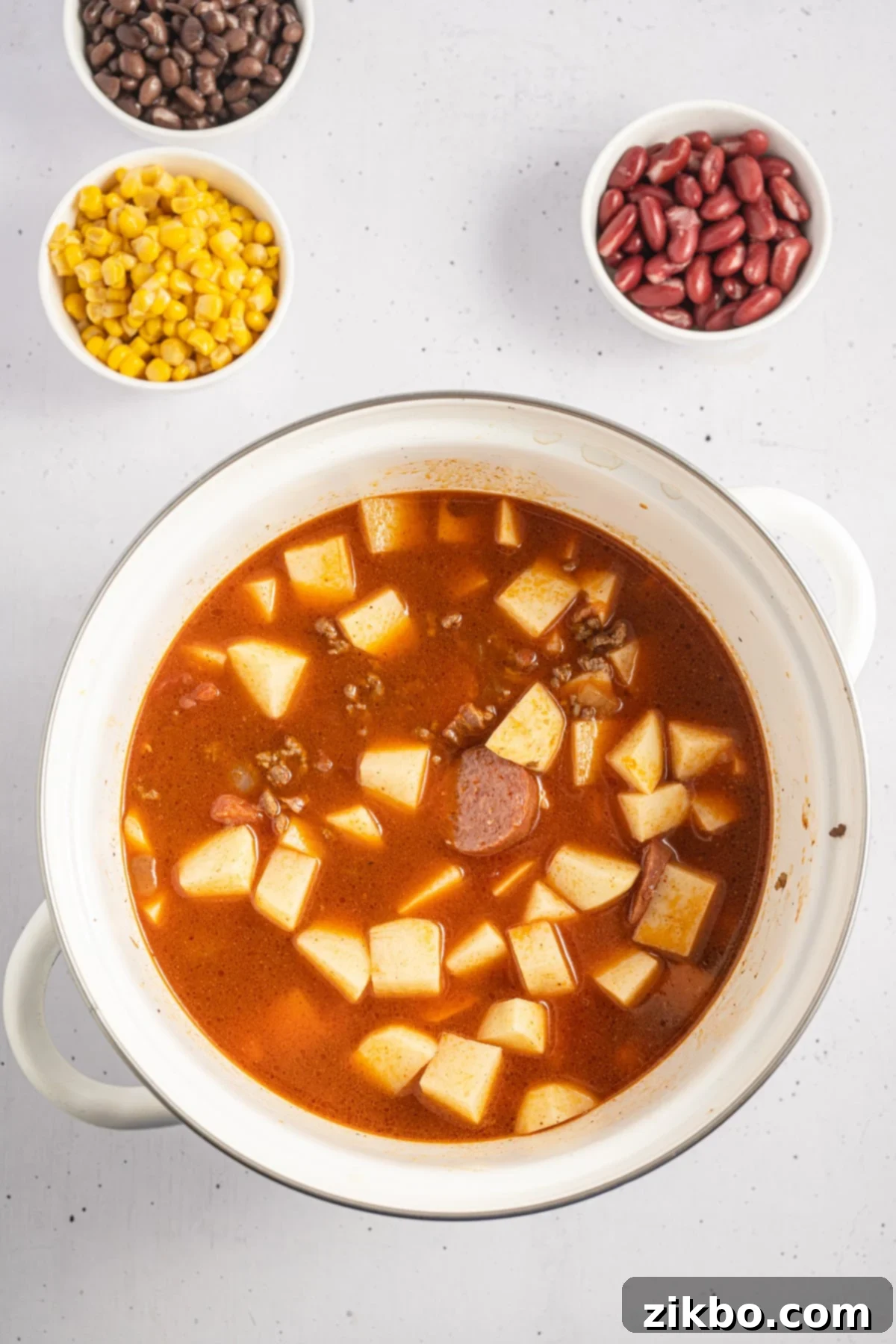 A soup pot filled with a savory broth and cubed potatoes.