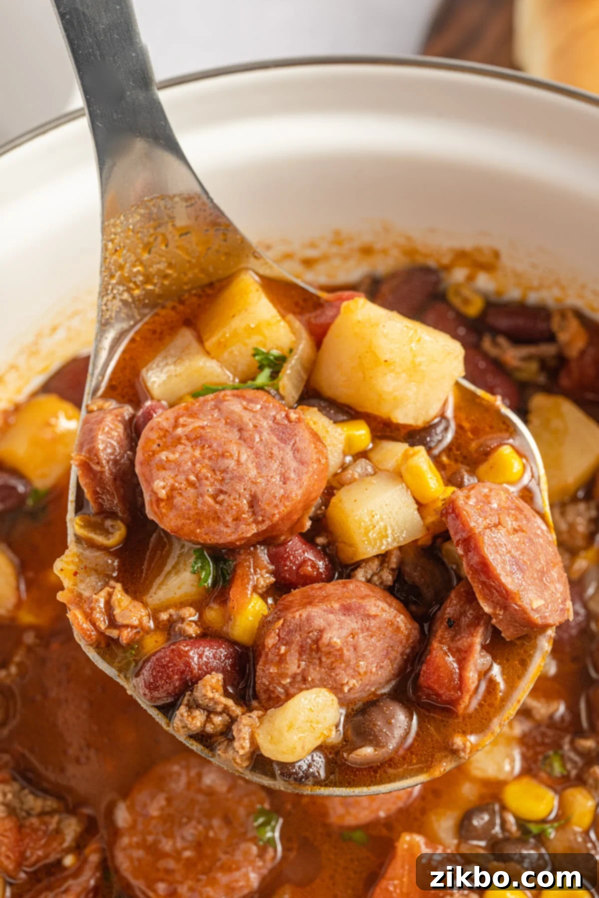 Scooping a ladleful of cowboy stew from a large pot.