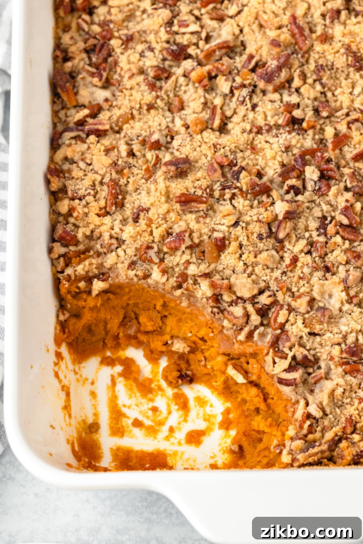 A baking dish filled with a finished sweet potato casserole, topped with a rich pecan streusel, ready to be served.