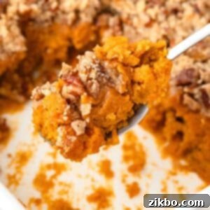A spoon scooping a portion of sweet potato casserole from a baking dish.