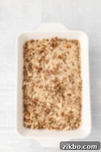 A baking dish filled with an unbaked sweet potato casserole with a pecan crumble.