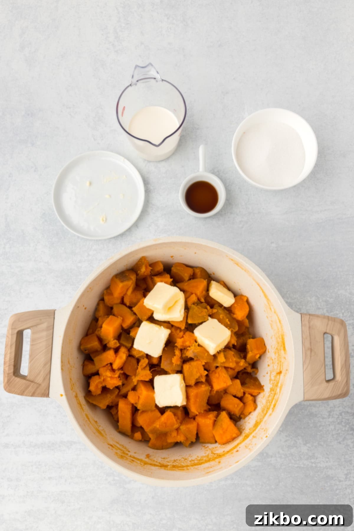 A pot filled with cooked sweet potatoes and a few pats of butter, steaming gently.