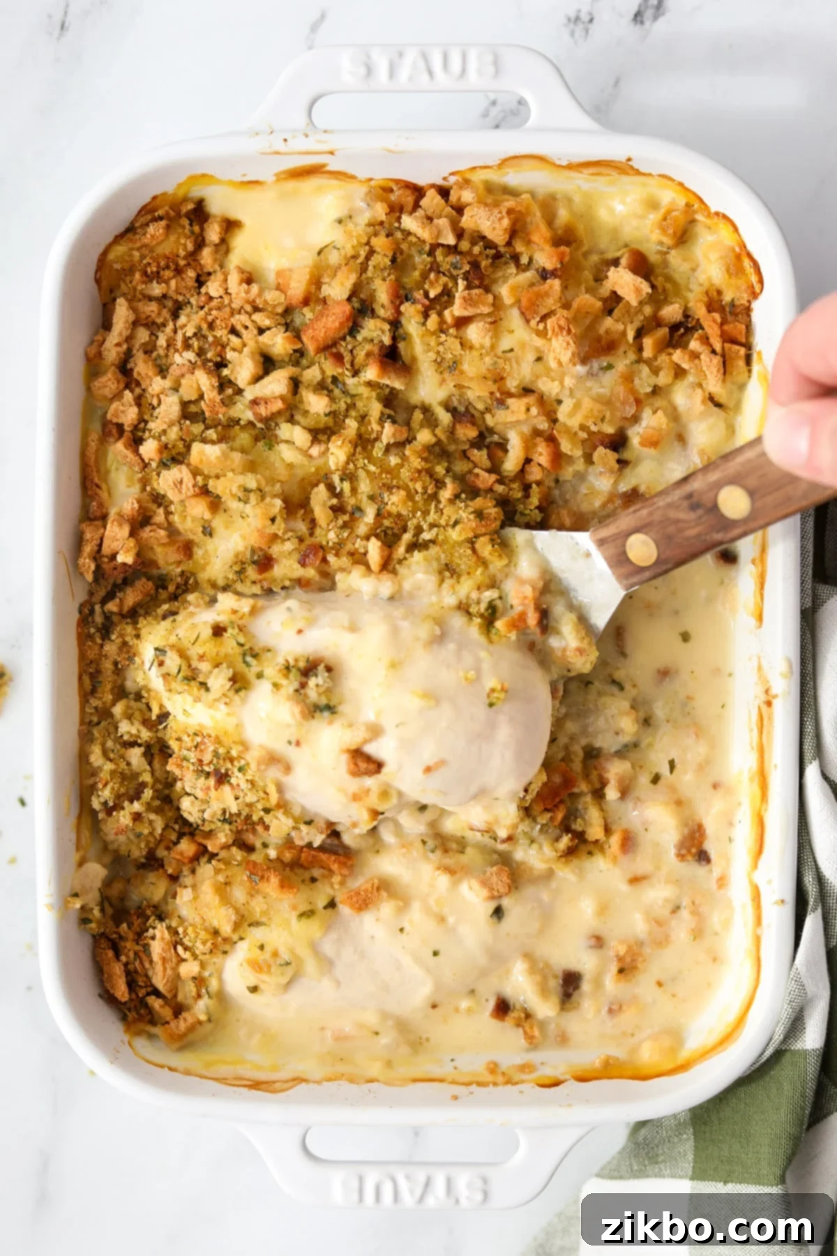 Lifting a generous serving of chicken and stuffing from the casserole dish onto a plate.