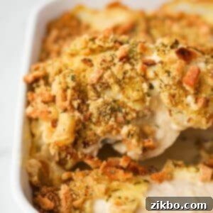 Lifting a piece of chicken and stuffing from a baking dish.