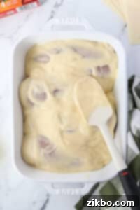 Spreading a soup mixture on top of chicken breasts.