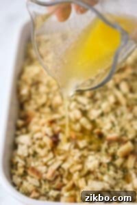 Drizzling butter on top of a stuffing and chicken casserole.