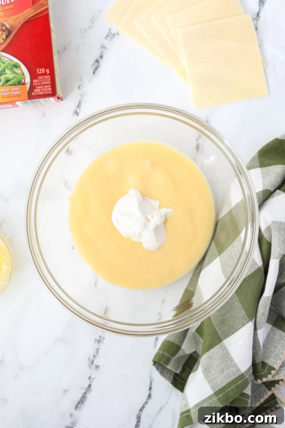 A bowl with cream of chicken soup and sour cream, ready to be mixed.