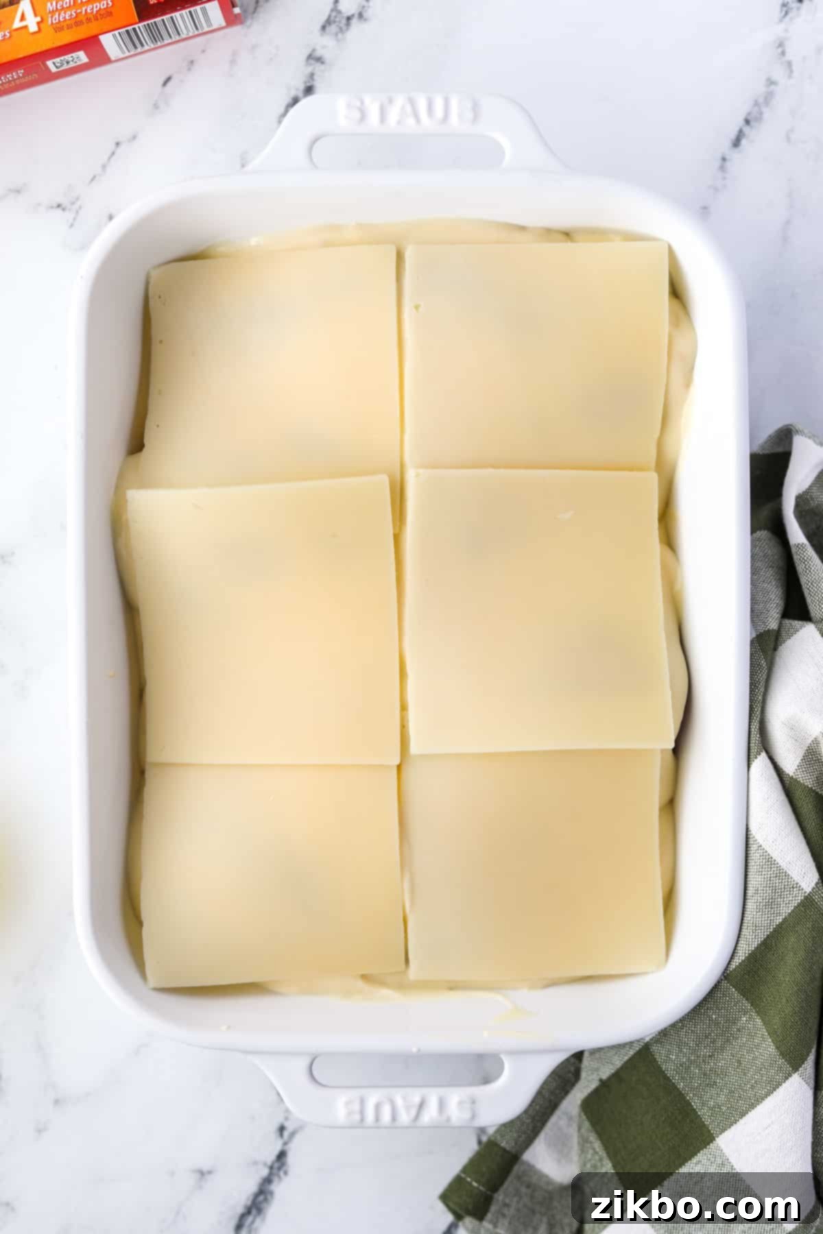 Topping a casserole with slices of Swiss cheese over the creamy chicken layer.