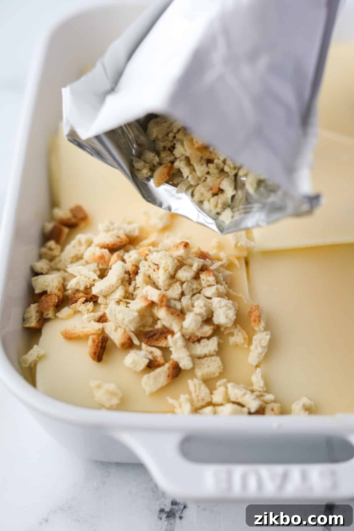 Sprinkling dry stuffing mix evenly on top of the Swiss cheese layer.
