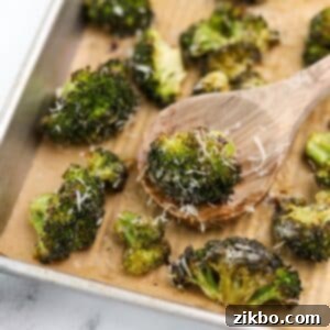 A wooden spoon taking a portion of roasted ranch broccoli from a baking sheet.