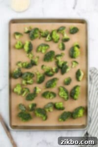 Broccoli florets spread onto a lined baking dish.
