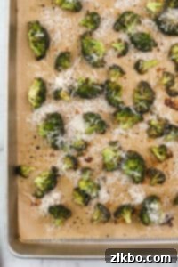 Roasted broccoli on a baking sheet topped with parmesan cheese.