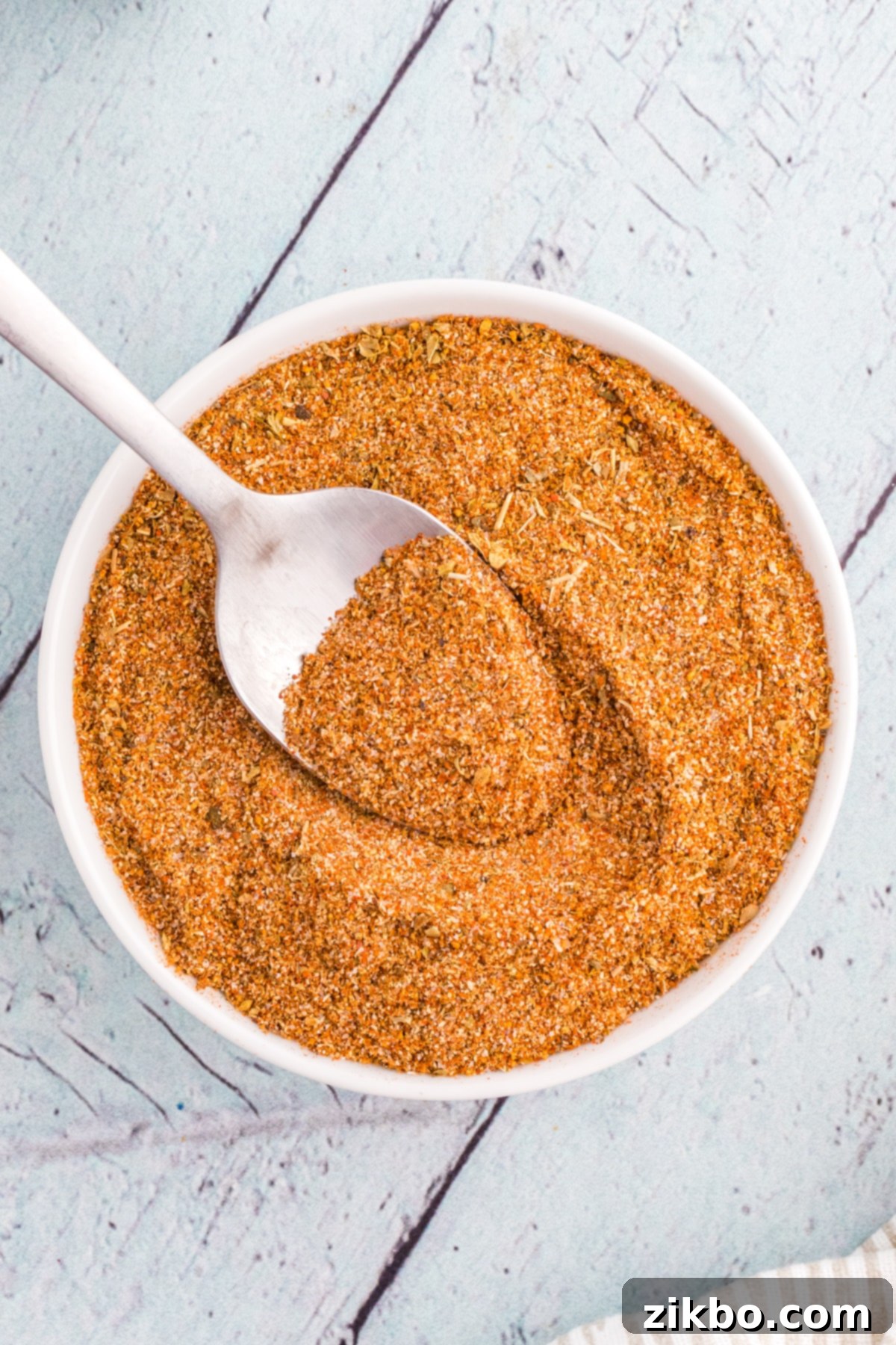 A small bowl with homemade seasoning blend, with a spoon sticking out of it.