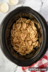 A slow cooker filled with cinnamon roll pieces.