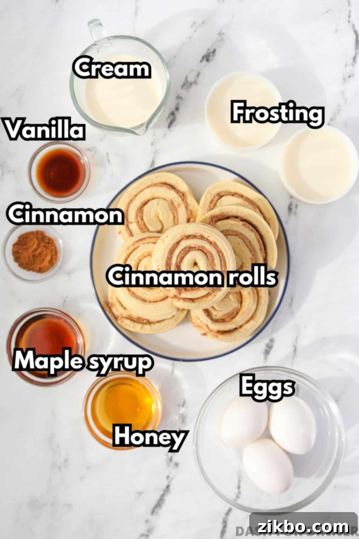 The ingredients needed to make cinnamon roll casserole: canned cinnamon rolls, frosting, eggs, heavy cream, honey, maple syrup, vanilla extract, and cinnamon.