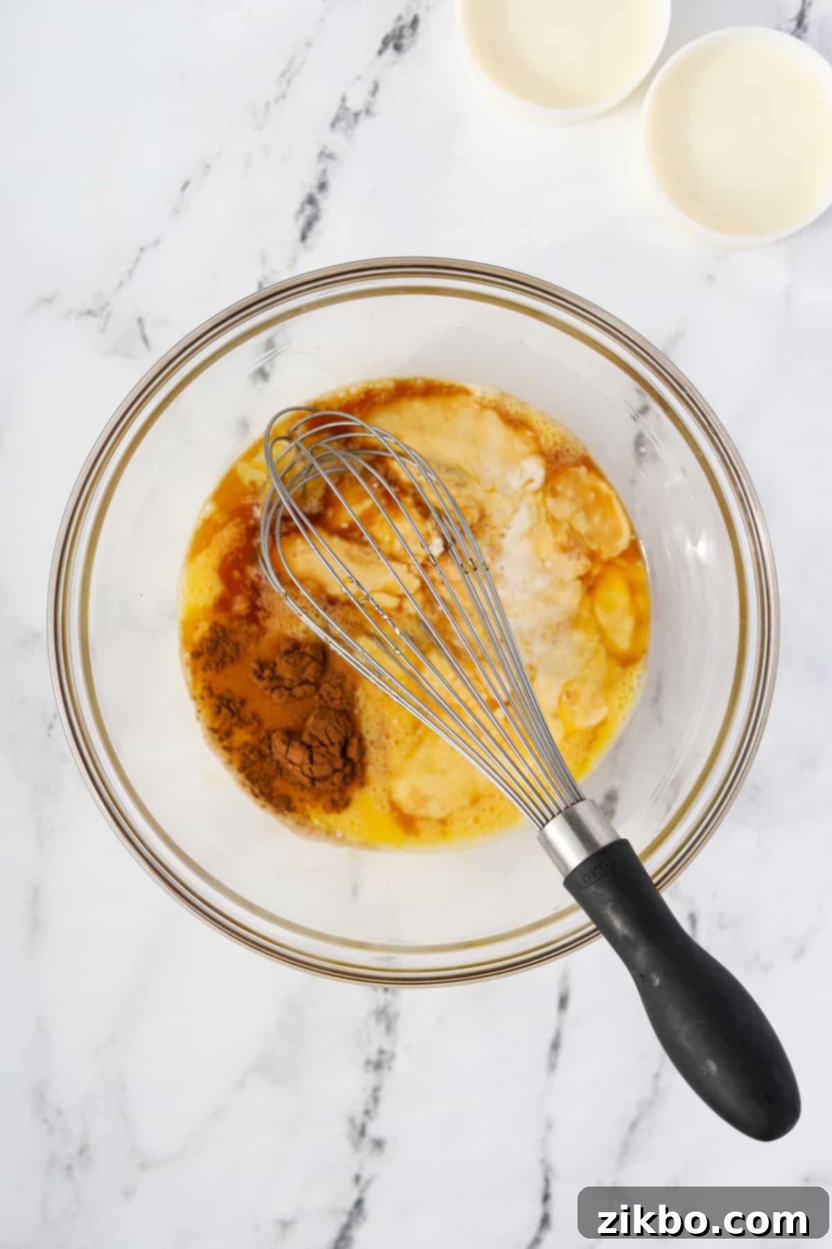 A bowl of eggs and heavy cream with vanilla and cinnamon added, ready to be whisked.