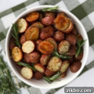 A white bowl filled with roasted baby potatoes, garnished with several sprigs of fresh rosemary for a beautiful presentation.