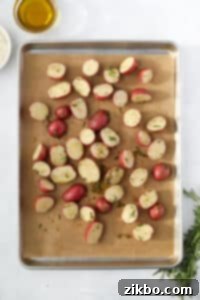 A sheet pan with potato halves spread out on a piece of parchment.
