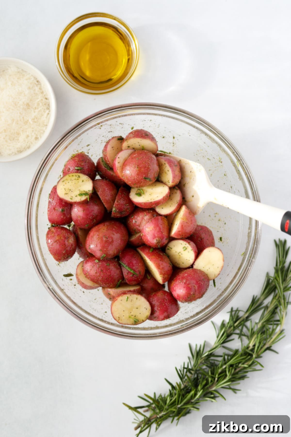 A large bowl of baby potatoes thoroughly tossed and coated in the aromatic seasoned oil mixture.
