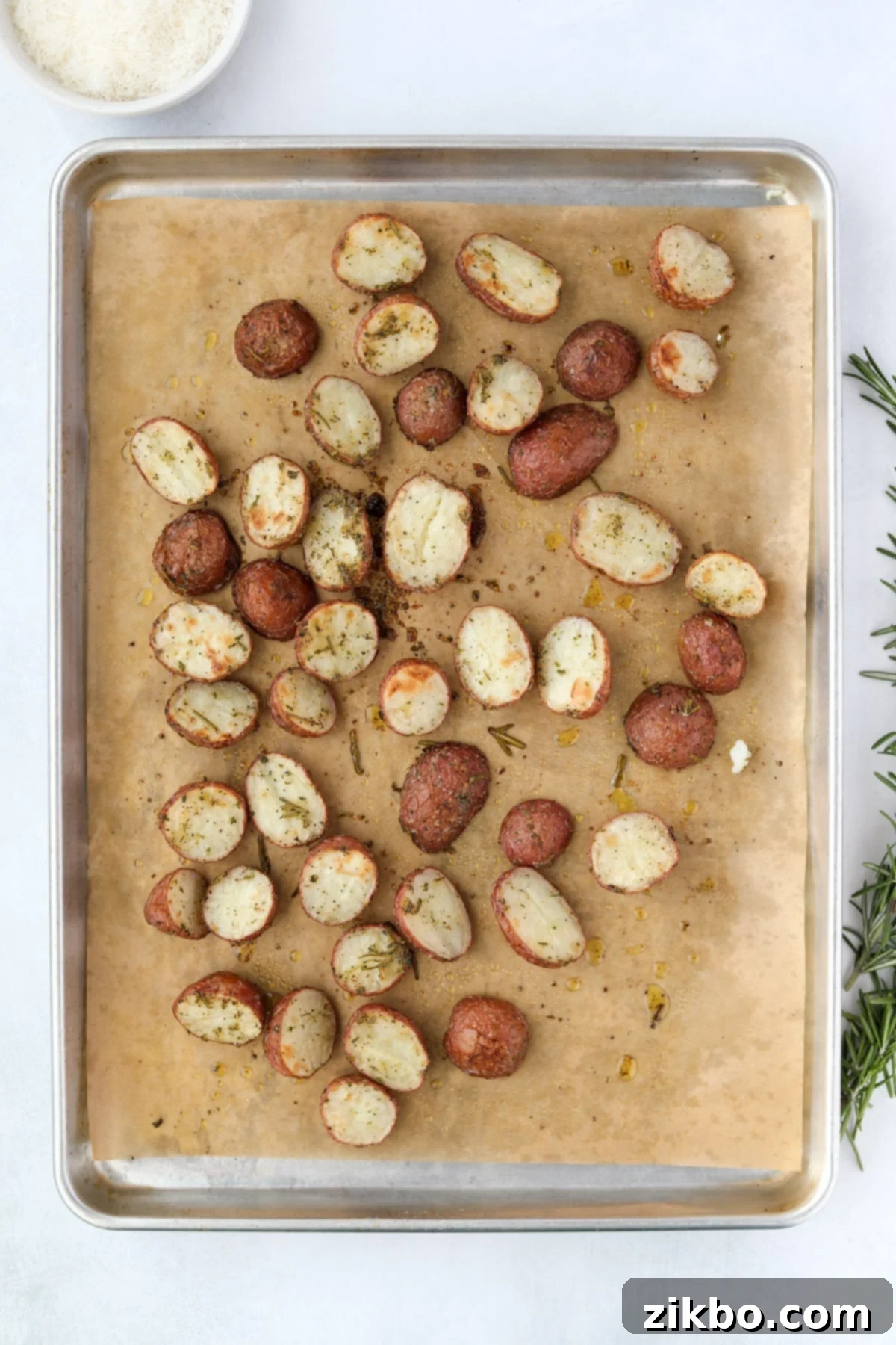A baking sheet of perfectly roasted, golden-brown baby potatoes, ready to be removed from the oven.