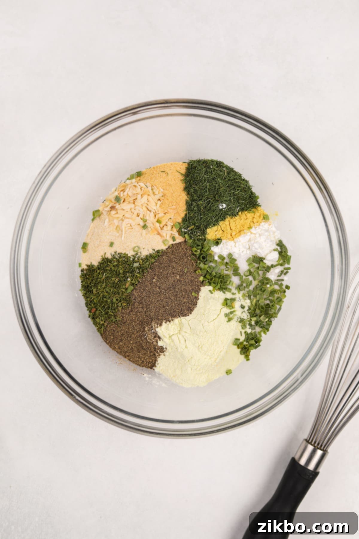 A bowl filled with a variety of dried herbs, seasonings, and salt, ready to be mixed for homemade ranch seasoning.