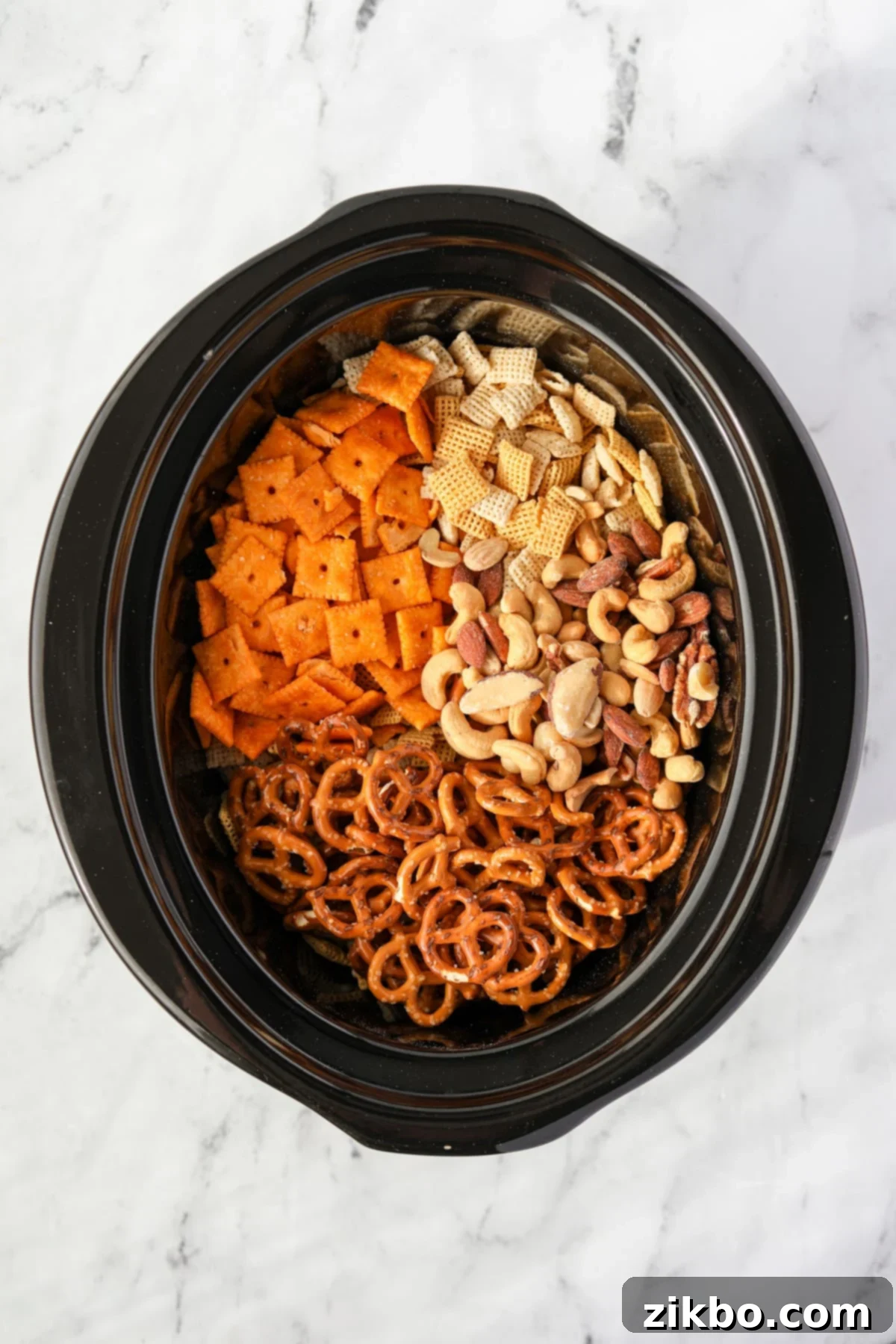 A slow cooker insert filled with dry ingredients for Chex Mix: various Chex cereals, pretzels, mixed nuts, and cheese crackers.