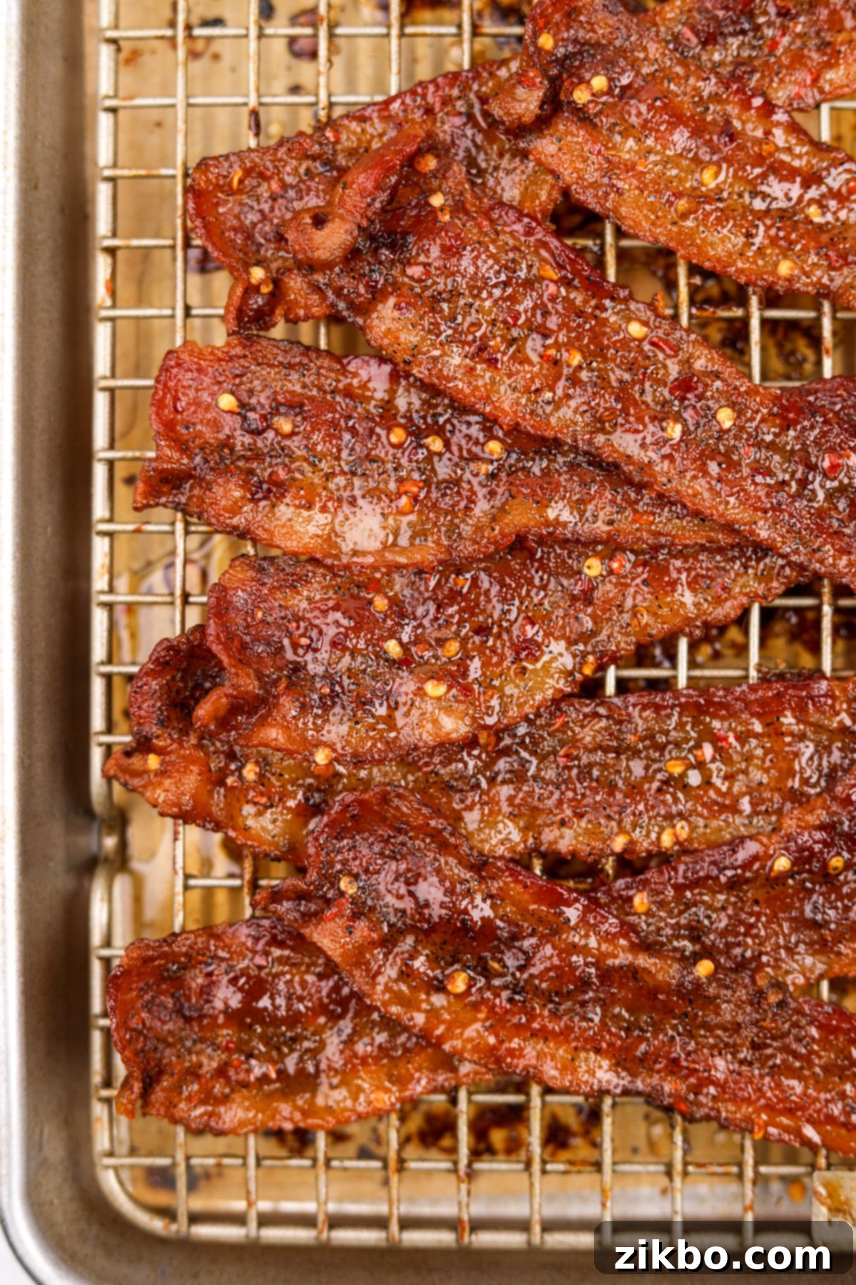 Bacon that has been candied with brown sugar, stacked elegantly on a wire baking rack, ready to serve.