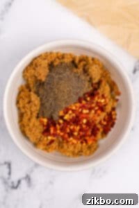 A small bowl with brown sugar, crushed chilies, and black pepper, mixed.