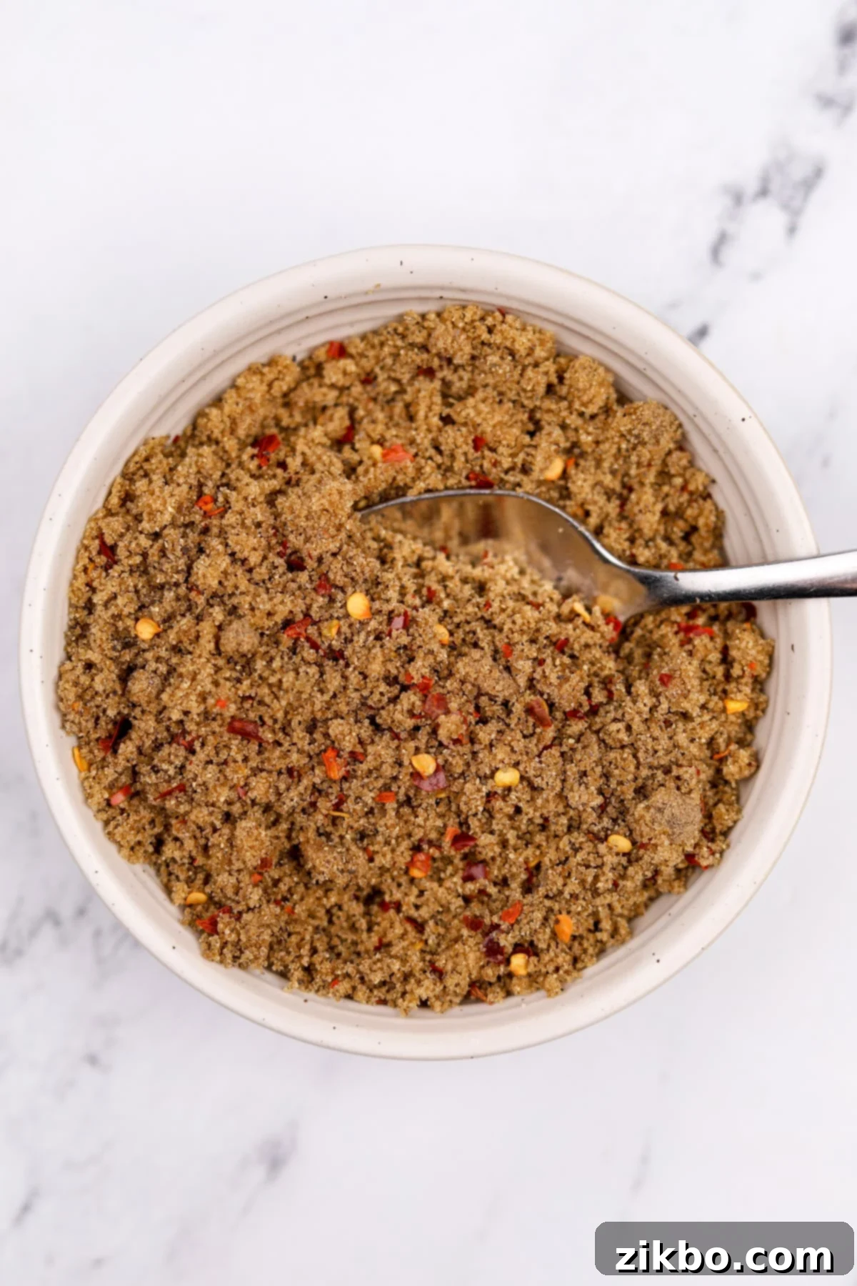 A small bowl with brown sugar, crushed chile flakes, and black pepper mixed together.