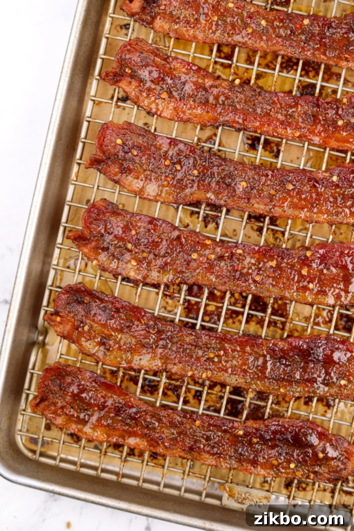 Crispy bacon on a wire rack that's been cooked with brown sugar and crushed chilies, showcasing its delicious glaze.