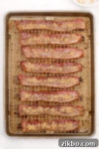 Bacon slices on a baking sheet, now flipped over and ready for the second sprinkle of brown sugar.