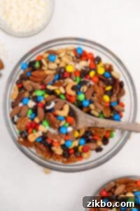 A large bowl filled with trail mix, including nuts and M&M's candies.