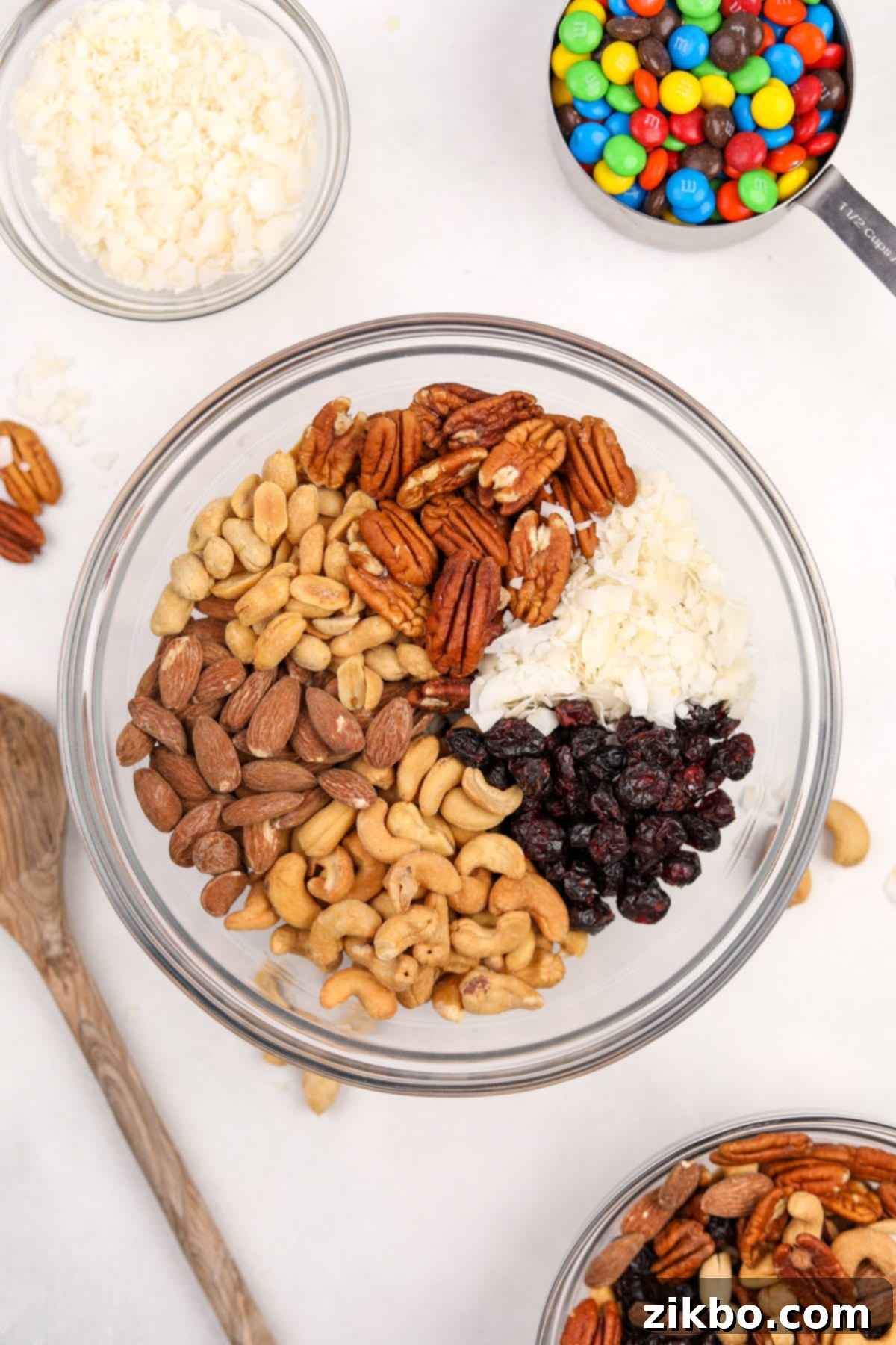 A bowl filled with different sections of nuts, coconut, and dried fruit, ready to be mixed.