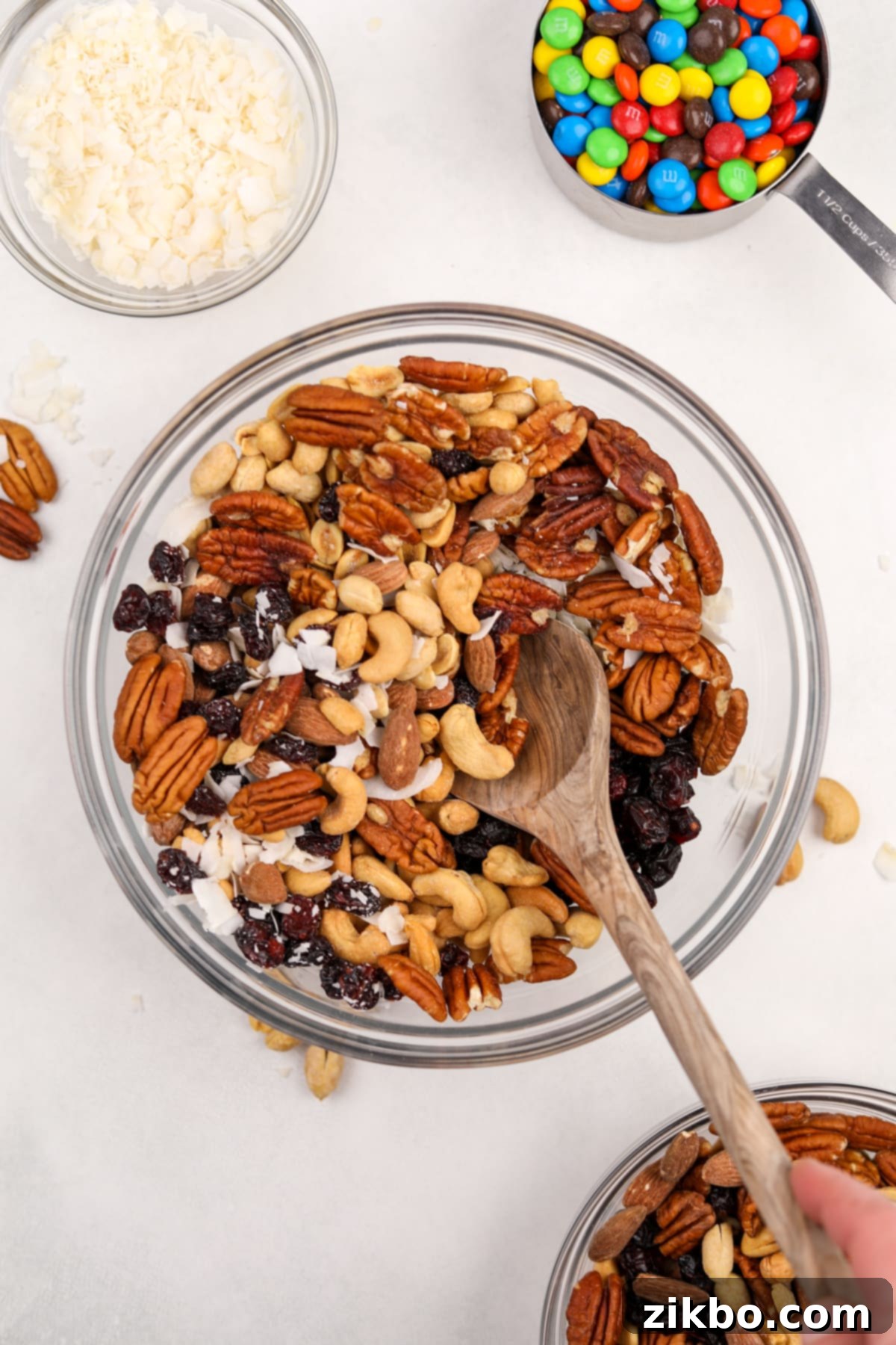 A large bowl filled with mixed nuts, dried fruit, and coconut after initial stirring.